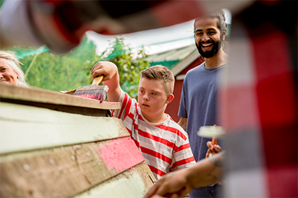 student works to paint shed boards red with adult team