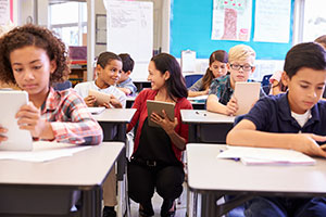 Teacher working with students on tablets