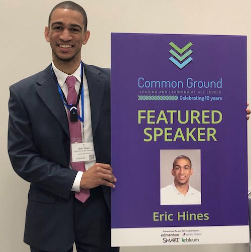 Man in suit standiing nexting to poster with the words  'Featured Speaker' and a picture of himself