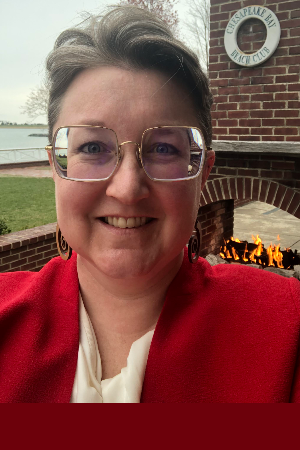 Headshot of Irene Bal, woman with short hair, large glasses, and a red blazer