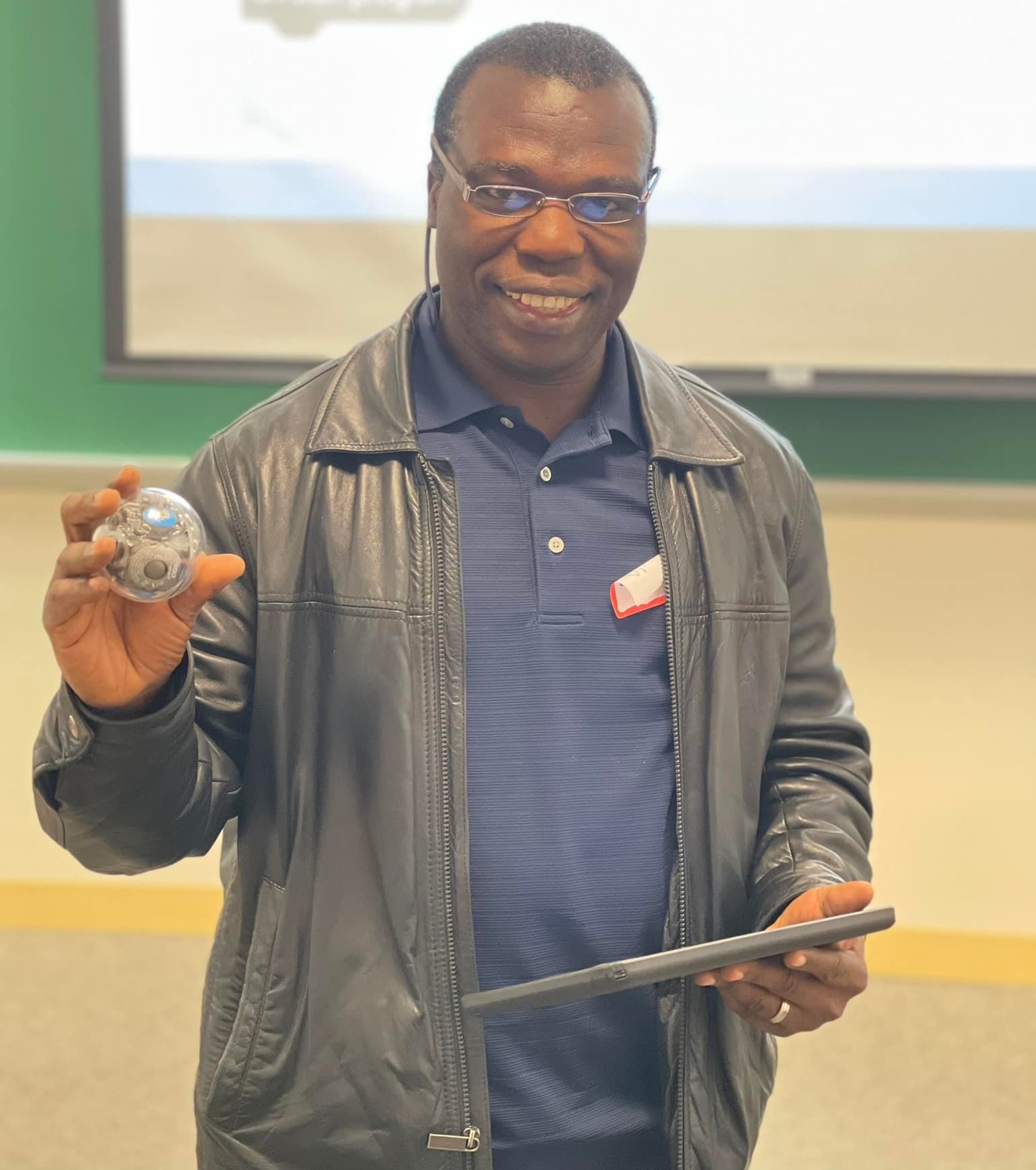 man with jacket and glasses holding an iPad and a Sphero ball