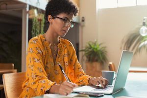 woman sitting at the compuer with pen in hand