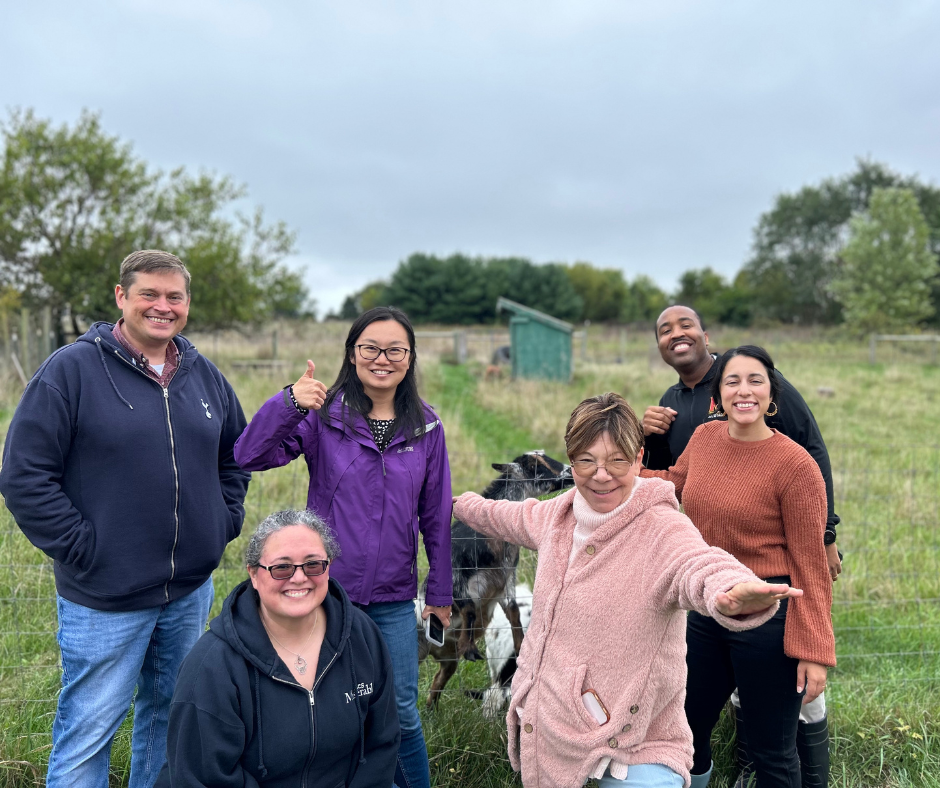 School Counseling Faculty smile with goats at a farm