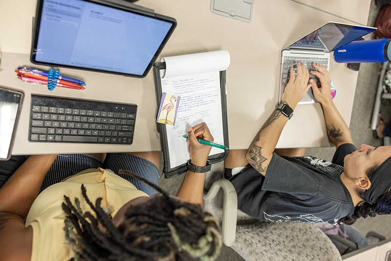 Graduate students collaborate during class using various forms of technology.