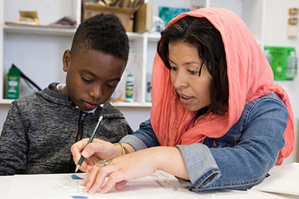 A female teacher working with a male student in a classroom
