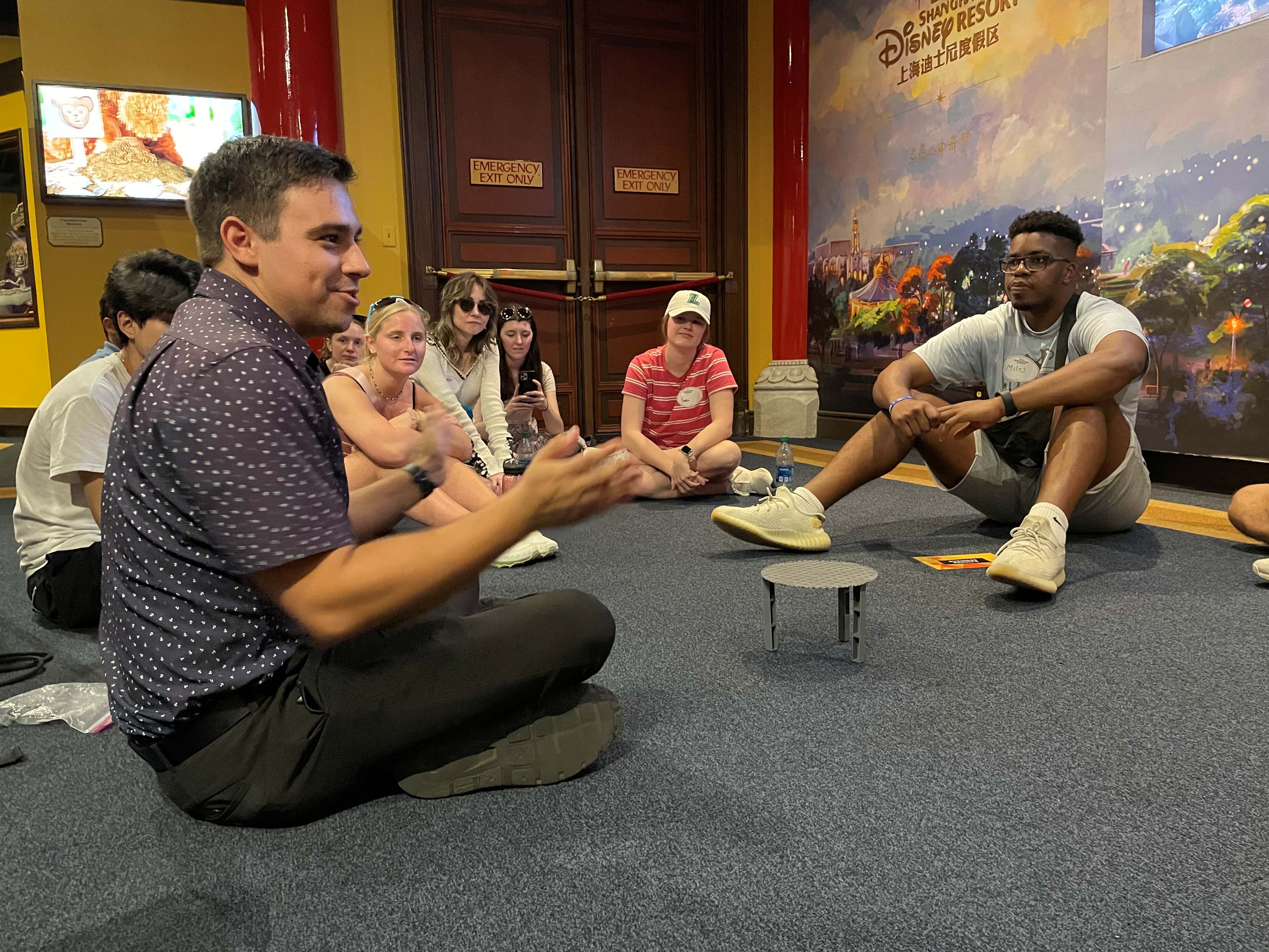 A group of Loyola students sit in a circle listening to a Disney Cast Member.