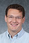 John Peter Krahel poses for a picture wearing a collared shirt and glasses