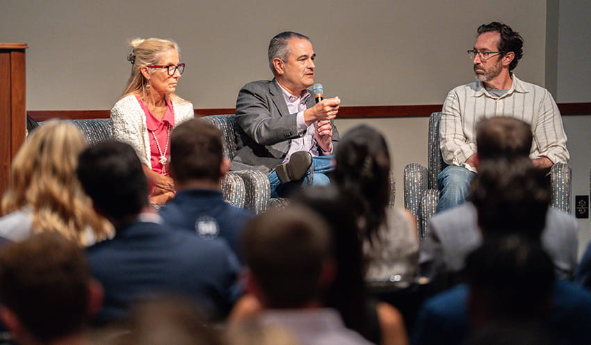 A panel of AI experts speaks to a crowd of students.