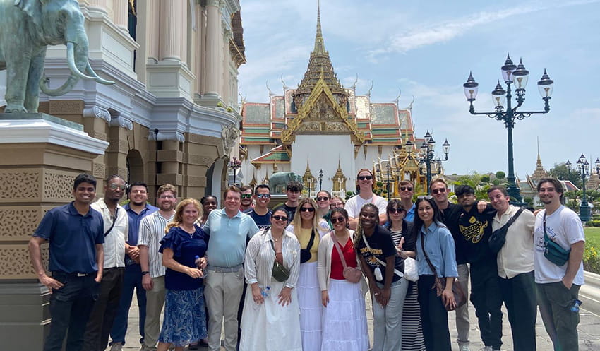 A group of graduate business students pose for a group photo while on an international field study trip to Thailand.