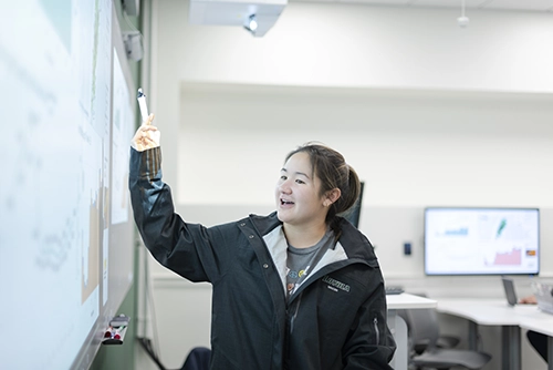 student points at board during presentation
