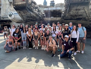 MK349 Customer Experience Management: The Disney Study Tour; Spring 2023, A marketing class group photo with students and professors standing in front of the Millennium Falcon from Star Wars at Walt Disney World
