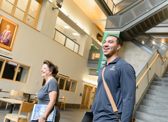 student and professor walking down the main stair in the Sellinger building