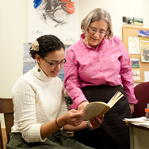 A student and professor looking at a book