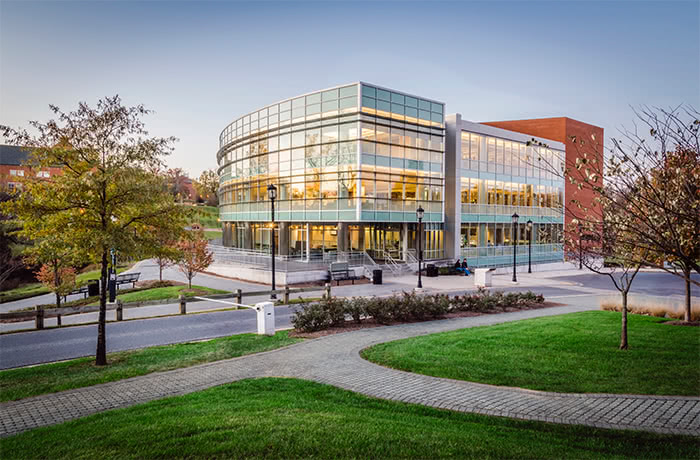 The glass facade of the Loyola Notre Dame Library at sunset with the warm glow of lights within