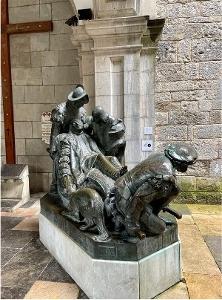 Bronze statue of a sick or ingured Ignatius Loyola being tended to by soliders