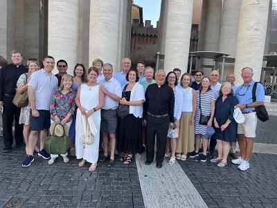A larger group gathers for a photo with stone columns behind them