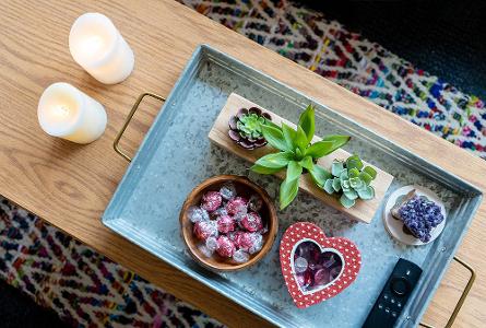 A tray with succulent plants, candies, and a remote