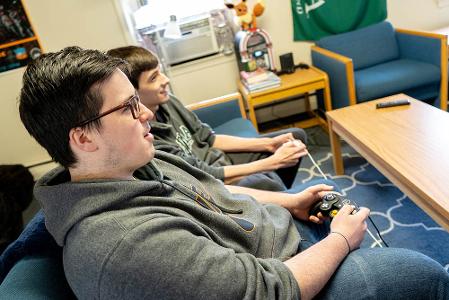 Two students playing videogames in a dorm lounge