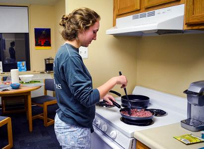 A student cooks ground beef in a kitchen area