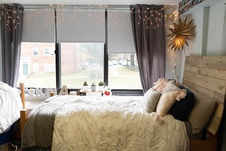 A dorm room with three windows, with a star paper lantern and string lights
