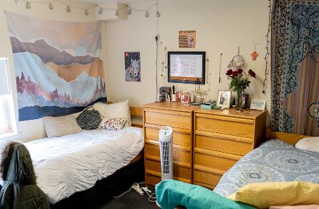 A dorm room decorated with tapestries and string lights