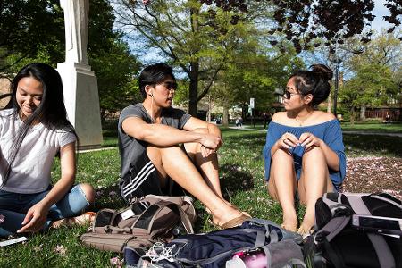 Students laughing while sitting in the grass on the quad