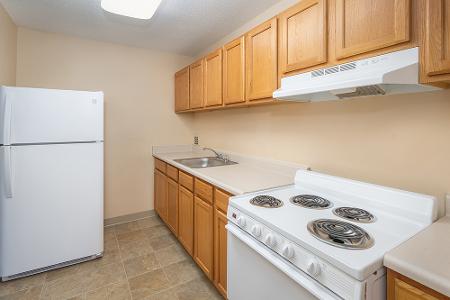 A kitchen with fridge, stove, sink, and kitchen cabinets.