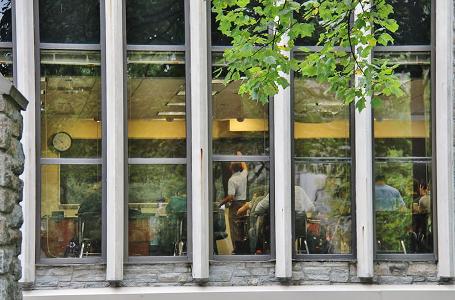 A view of a classroom from the exterior of Donnelly Science Center, where a professor is writing on the chalkboard.