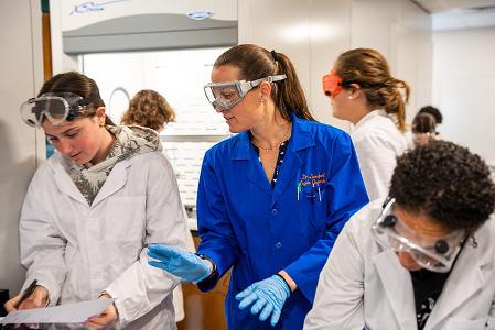 Students with safety glasses and gloves with a Chemistry professor.