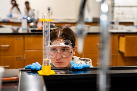 A student reading the gauge on a beaker in a chemistry lab.