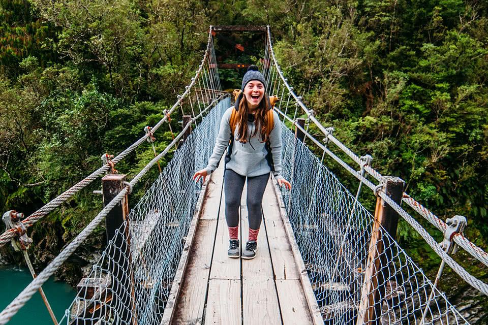 Student standing and smiling on a wooden bridge