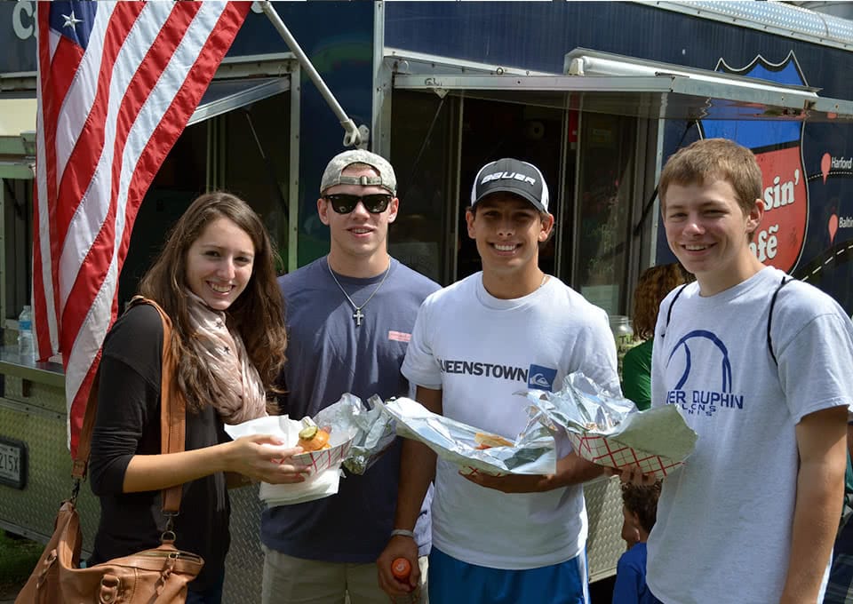 Students posing with food in front of a food truck