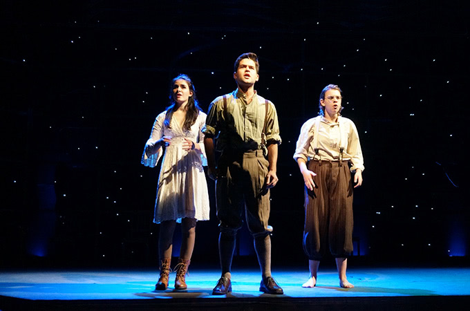 Three students singing on stage in front of a starry backdrop