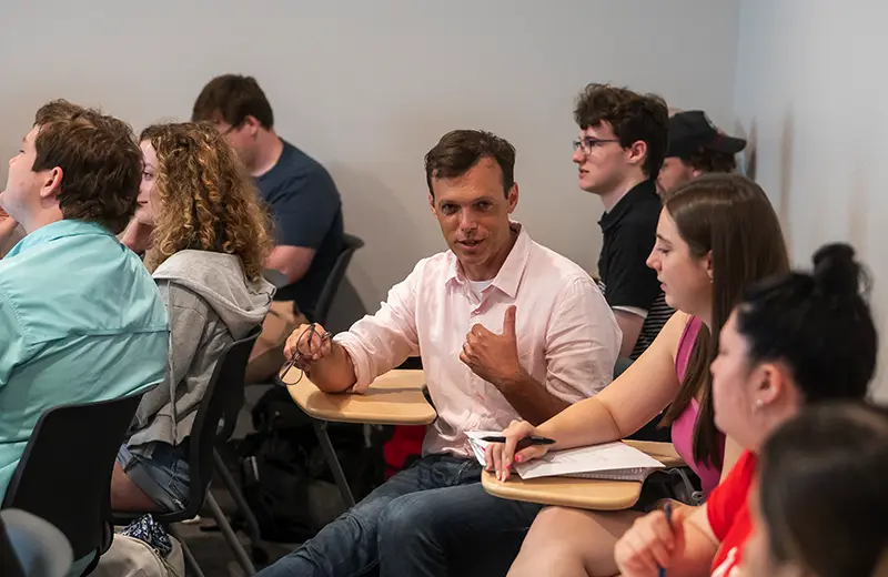 A professor sitting and talking with students during a class