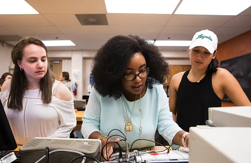 A professor and two students working with electrical engineering equipment