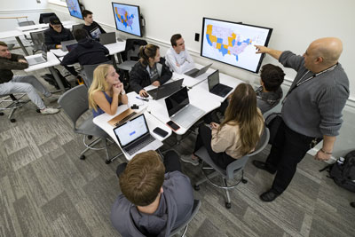 Professor and students work on data visualization project in collaborative setting